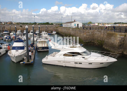 Ein Besuch Motor Cruiser Manöver seine Position neben anderen Yachten und Boote in den Hafen der Stadt Porthcawl, Wales Stockfoto