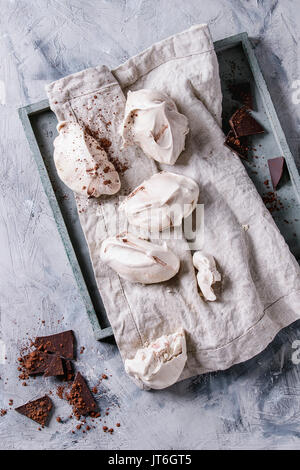 Backen hausgemachte französische Dessert Meringue mit Schokolade mit dunklen Zerkleinern von Schokolade und Kakaopulver auf Textil serviette Holz- fach über graue Co serviert. Stockfoto