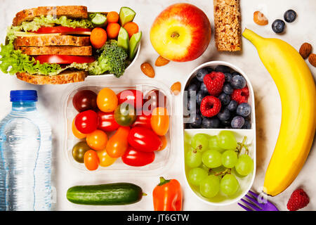 Gesunde Brotdose mit Sandwich und frisches Gemüse, eine Flasche Wasser und Obst auf Holz- Hintergrund. Ansicht von oben Stockfoto