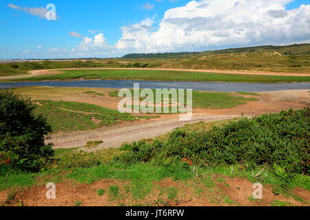 Ein Blick über den Fluss Ogmore zur Myrthyr Mawr Sanddünen mit Newton Dorf im Hintergrund an einem schönen sonnigen Tag. Stockfoto