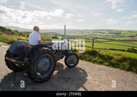 Landwirt Erinnerungen auf alten Traktor bei Ackerland Landschaft suchen Stockfoto