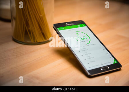 London, Großbritannien. Samsung Smartphone mit Diät tracking App vor Glas Spaghetti. Stockfoto