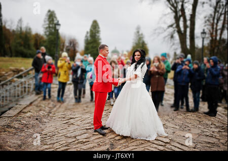 Wunderschöne Hochzeit Paar, Hände auf dem Bürgersteig während die Masse der Kinder nimmt Bilder von Ihnen. Stockfoto