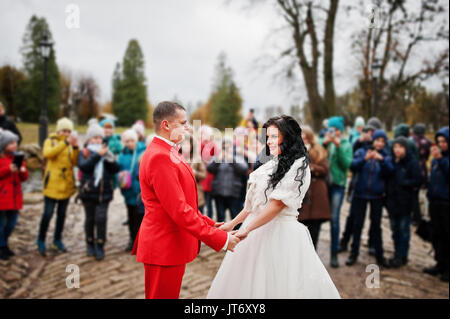 Wunderschöne Hochzeit Paar, Hände auf dem Bürgersteig während die Masse der Kinder nimmt Bilder von Ihnen. Stockfoto