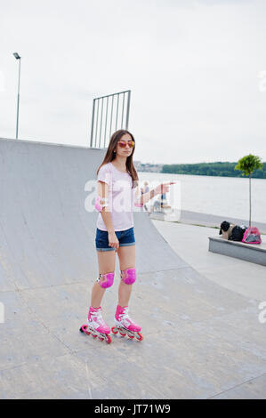 Porträt einer wunderschönen jungen Frau rollerblading im Freien auf der Rollschuhbahn. Stockfoto