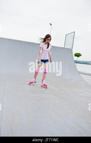 Porträt einer wunderschönen jungen Frau rollerblading im Freien auf der Rollschuhbahn. Stockfoto