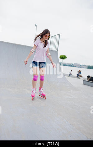 Porträt einer wunderschönen jungen Frau rollerblading im Freien auf der Rollschuhbahn. Stockfoto