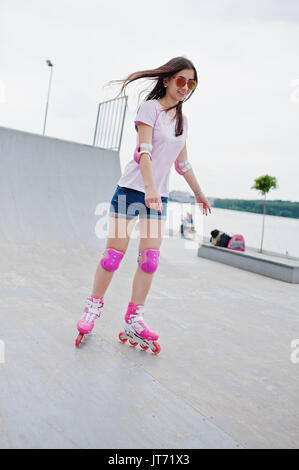 Porträt einer wunderschönen jungen Frau rollerblading im Freien auf der Rollschuhbahn. Stockfoto