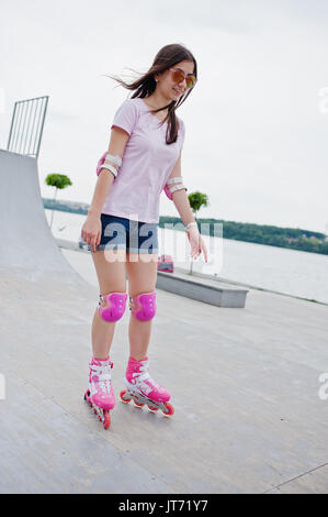 Porträt einer wunderschönen jungen Frau rollerblading im Freien auf der Rollschuhbahn. Stockfoto