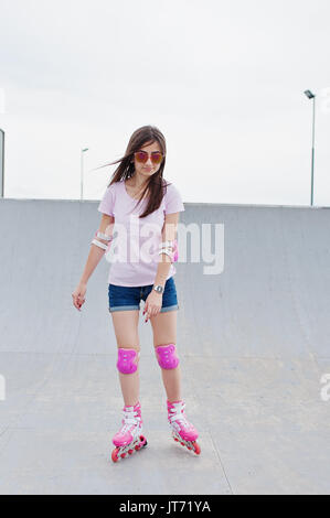 Porträt einer wunderschönen jungen Frau rollerblading im Freien auf der Rollschuhbahn. Stockfoto