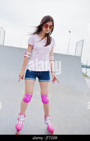 Porträt einer wunderschönen jungen Frau rollerblading im Freien auf der Rollschuhbahn. Stockfoto