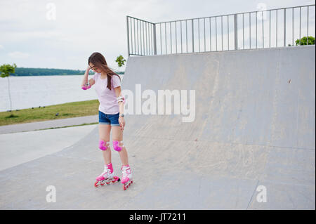 Porträt einer wunderschönen jungen Frau rollerblading im Freien auf der Rollschuhbahn. Stockfoto