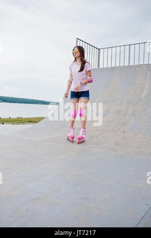 Porträt einer wunderschönen jungen Frau rollerblading im Freien auf der Rollschuhbahn. Stockfoto