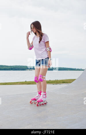 Porträt einer wunderschönen jungen Frau rollerblading im Freien auf der Rollschuhbahn. Stockfoto