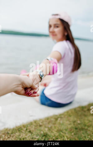 Nahaufnahme von Paar halten sich an den Händen, während er auf dem Boden neben dem See. Stockfoto