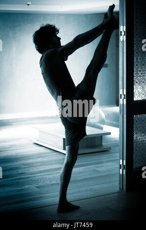 Männliche Yogalehrer tun teilt Bein Strecken Flexibilität Gymnastik und Yoga Asanapraxis im Fitness-Studio Stockfoto
