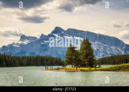 Touristen genießen einen sonnigen Tag am See im Banff National Park mit Mt. Rundle zwei Jack im Hintergrund. Stockfoto