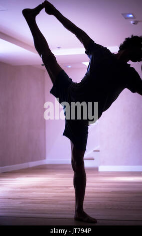 Männliche Yogalehrer tun teilt Bein Strecken Flexibilität Gymnastik und Yoga Asanapraxis im Fitness-Studio Stockfoto