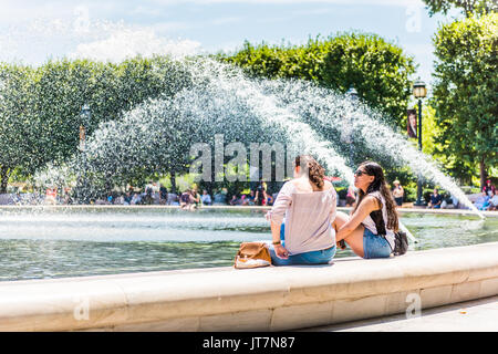 Washington DC, USA - Juli 3, 2017: Junge Mädchen Frauen sitzen auf plätschernden Springbrunnen in der skulpturengarten der Nationalgalerie im Sommer auf N Stockfoto