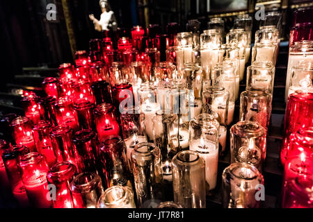 Rote und weiße Votivkerzen mit gelber Flamme in der Kirche Stockfoto