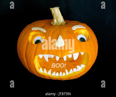 Diese scary Jack-o'-Lantern Gesicht, das geschnitten wurde in einen ausgehöhlten Kürbis mit orange Sun erweitert wurde - gebleicht weiß Seashells für Zähne, Nase, Augenbrauen, plus ein paar Kunststoff Spielzeug Augen. (Der weisse 'Buh!' wurde digital zum Bild hinzugefügt.) Carving Jack-o'-lanterns ist eine Tradition für Halloween, die von All Hallows' Eve entwickelt und setzt jährlich gefeiert werden, am 31. Oktober. Stockfoto