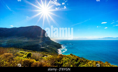 Niedrige Winter Sonne wirft ihre Strahlen über Smitswinkel Bay auf der Kap Halbinsel in der Western Cape Provinz von Südafrika unter blauem Himmel Stockfoto