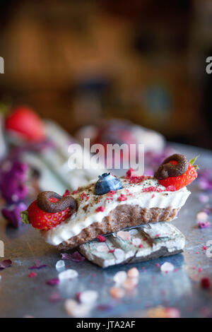 Veganer Käsekuchen Bissen mit Cashew Creme, mit Schokolade überzogene Erdbeeren und Heidelbeeren, Finger sortierte Snack. Stockfoto