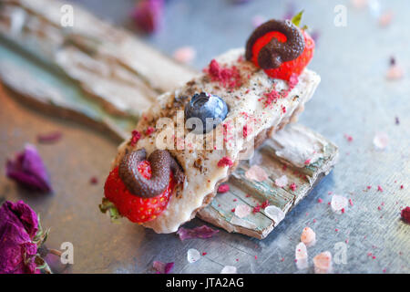 Veganer Käsekuchen Bissen mit Cashew Creme, mit Schokolade überzogene Erdbeeren und Heidelbeeren, Finger sortierte Snack. Stockfoto