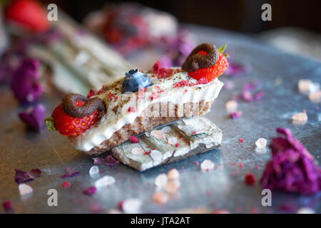 Veganer Käsekuchen Bissen mit Cashew Creme, mit Schokolade überzogene Erdbeeren und Heidelbeeren, Finger sortierte Snack. Stockfoto