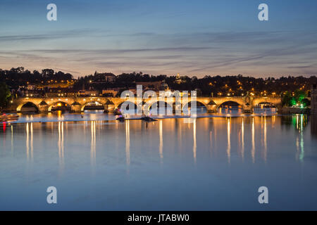 Leuchtet die Karlsbrücke (Karluv most) und seine Reflexionen auf der Moldau in Prag, Tschechische Republik, in der Dämmerung. Stockfoto