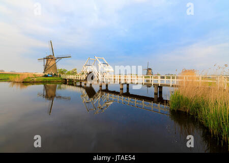 Traditionellen Windmühlen und die Brücke über den Kanal von Sunrise, Kinderdijk, UNESCO, Molenwaard, Südholland, Niederlande Stockfoto