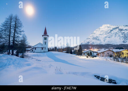 Licht der Dämmerung auf Chiesa Bianca und Alpine Village mit Schnee bedeckt, Malojapass, Engadin, Kanton Graubünden, Schweiz Stockfoto