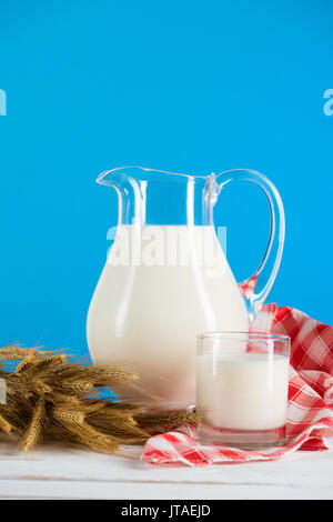 Nahaufnahme der frische Biomilch in Glas und Kanne mit Weizen Ohren auf hölzernen Tisch Stockfoto