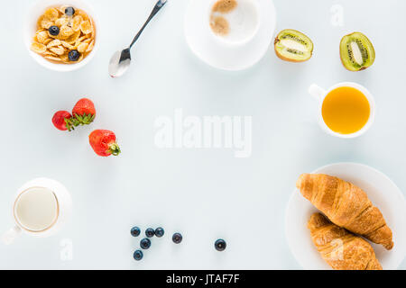 Draufsicht auf das leckere Frühstück mit Croissants, Kaffee und Erdbeeren auf der Tischplatte Stockfoto