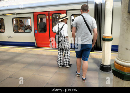 Frau im Sommer Hut und Hose auf der Plattform an der High Street Kensington U-Bahnstation in West London, UK KATHY DEWITT Stockfoto