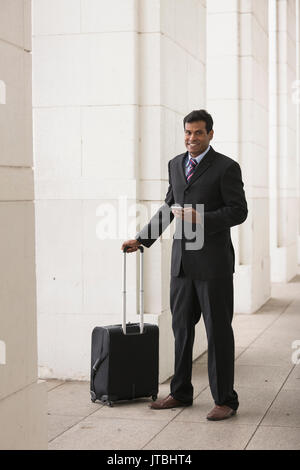Indische Geschäftsmann mit seinem Smart Phone im Freien in einer asiatischen Stadt. Stockfoto