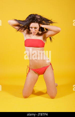 Schöne brünette Mädchen im Studio mit gelben Tapete Tragen eines Baywatch roten Bikini Stockfoto