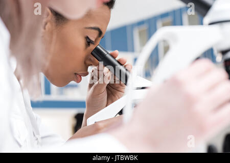 Junge afrikanische amerikanische Wissenschaftler arbeiten mit Mikroskop im chemischen Labor Stockfoto