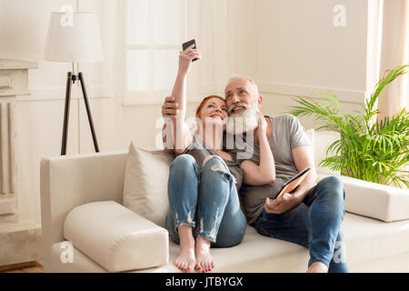 Gerne reifes Paar unter selfie während auf dem Sofa zu Hause sitzen Stockfoto