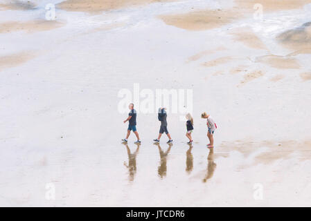 Eine Familie der Urlauber wandern in einzelne Datei auf einem Strand in Newquay, Cornwall. Stockfoto