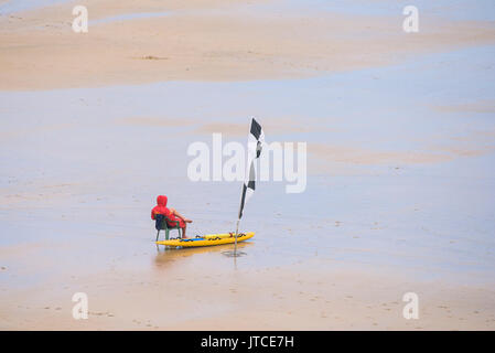 Ein einsamer RNLI Rettungsschwimmer an einem ruhigen Strand in Newquay, Cornwall. Stockfoto