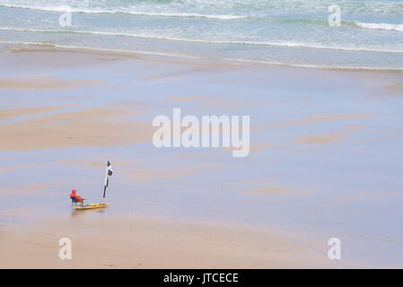 Ein einsamer RNLI Rettungsschwimmer an einem ruhigen abgelegenen Strand in Newquay, Cornwall. Stockfoto