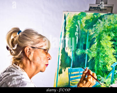 Blond, Pony-tailed Senior Professional arbeiten auf eine Leinwand, auf der Basis einer Foto sie in Giverny, Frankreich nahm, auf dem Anwesen von Claude Monet. (Ar Stockfoto