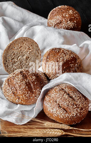 Integral Brötchen mit verschiedenen Samen auf weißem Handtuch für die Küche. Stockfoto