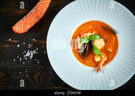 Hausgemachte Meeresfrüchtesuppe mit Tomatensauce und Kokosmilch auf einem alten Holz Fach Stockfoto