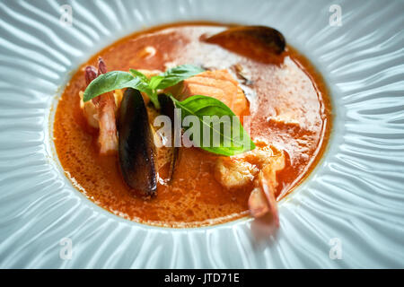Hausgemachte Meeresfrüchtesuppe mit Tomatensauce und Kokosmilch auf einem alten Holz Fach Stockfoto