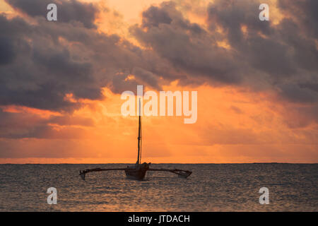 Dhow Boot in der frühen Morgensonne Silhouette durch Wolken über dem Indischen Ozean Diani, Kenia