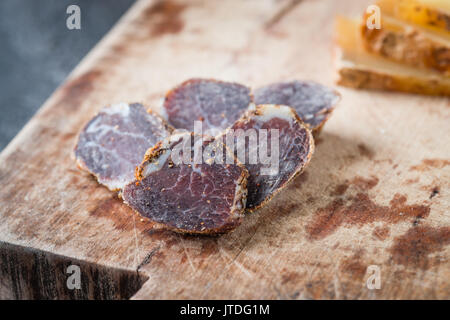 In Scheiben geschnittene Hausgemachte getrocknetes Fleisch Salami in Scheiben geschnitten und italienischen Käsesorten Pecorino toscano auf alten Holz- Board Stockfoto