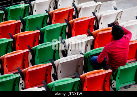 Klappbare Stühle aus Kunststoff in grün, weiß, rot, orange bei einer Veranstaltung. Diese sind häufig in Konzertsälen, in Stadien, Rennstrecken, wo große Menschenmengen Sitzen Stockfoto