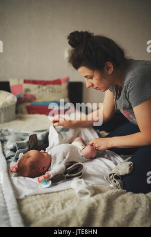 Junge Mutter ändern Baby Kleidung Stockfoto